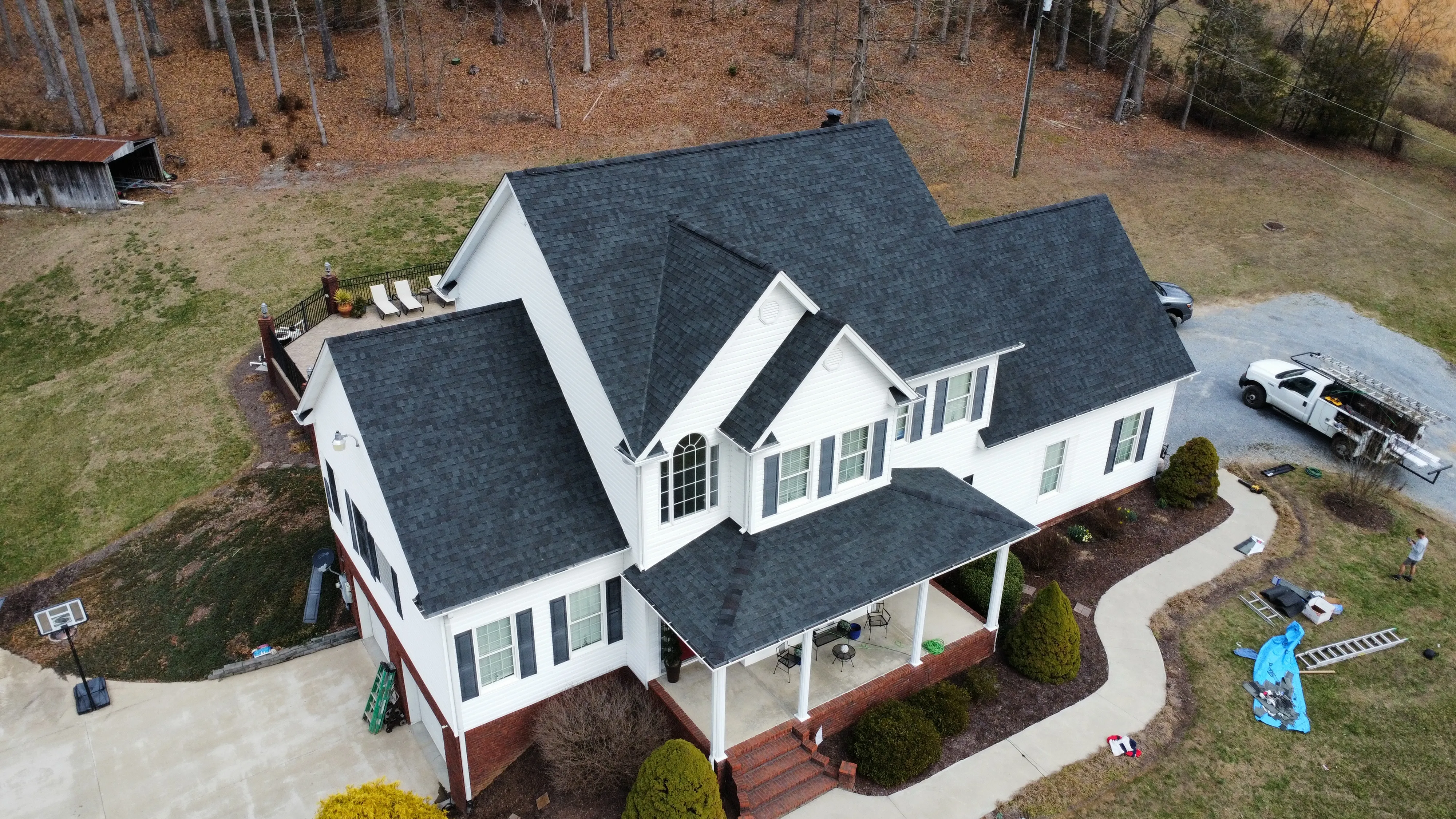 Two-story home with a dark grey shingle roof by White's Roofing Co