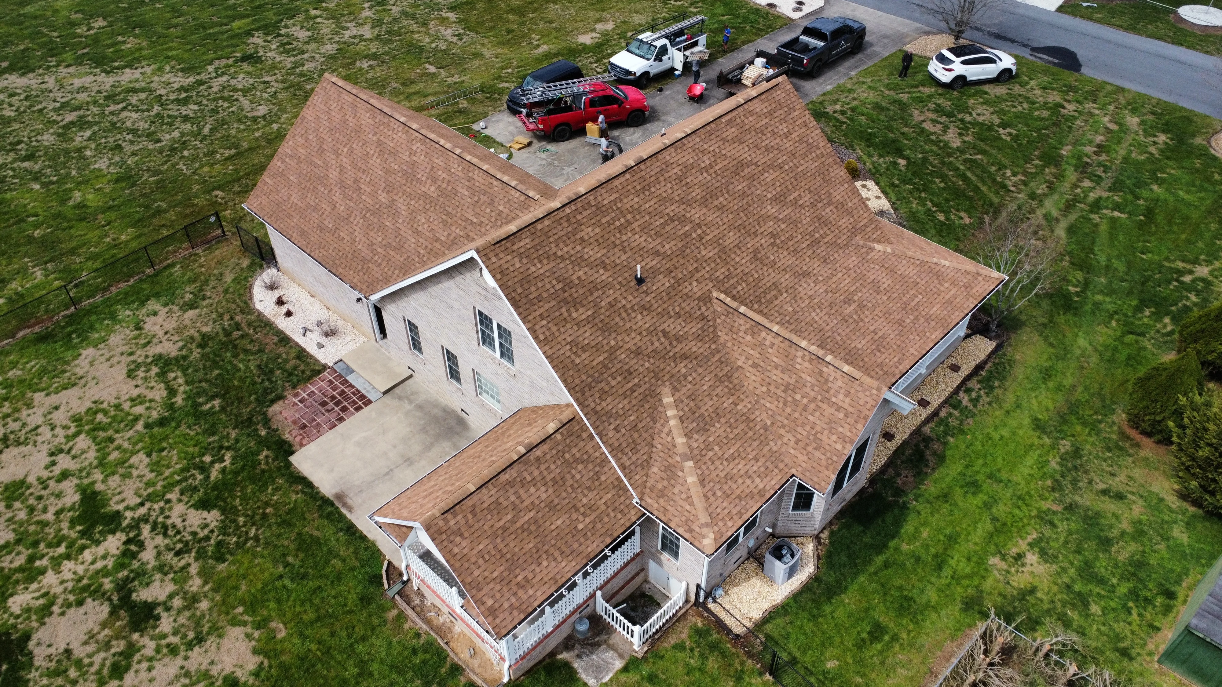 White’s Roofing Co crew and trucks at a home with a new brown shingle roof - Bristol, TN