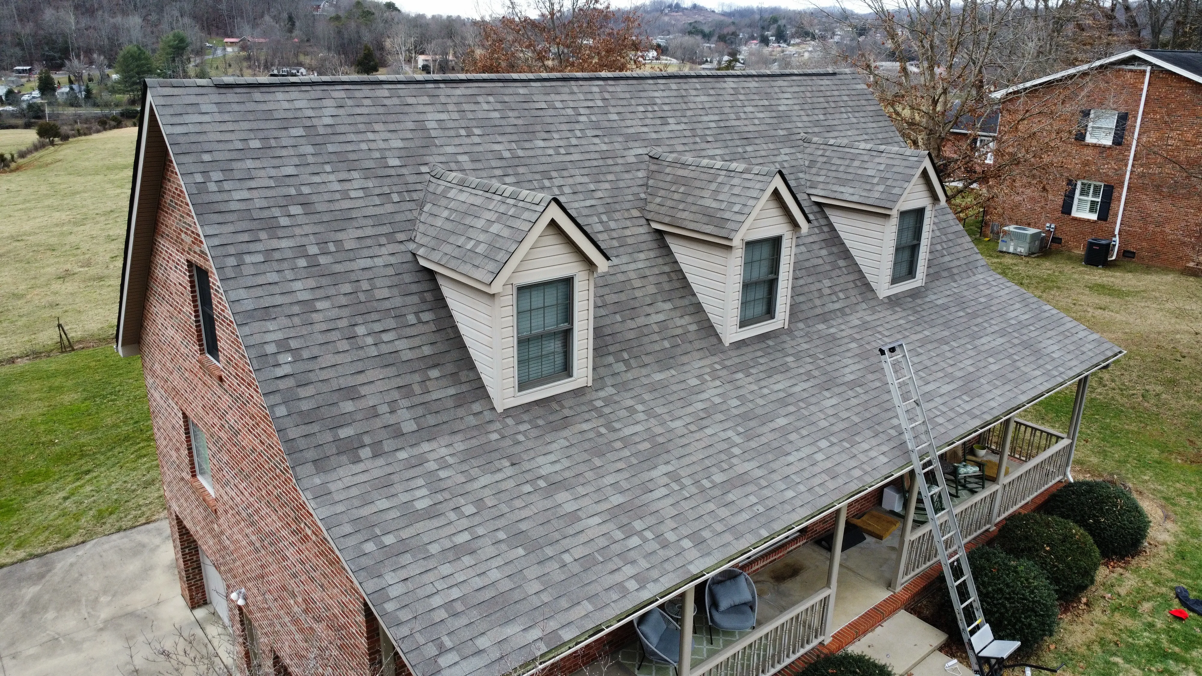 Brick home with dormers and a finished roof by White's Roofing Co